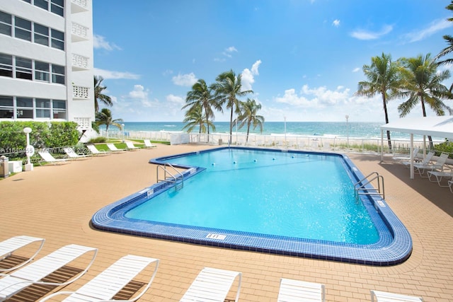 view of swimming pool featuring a view of the beach and a water view