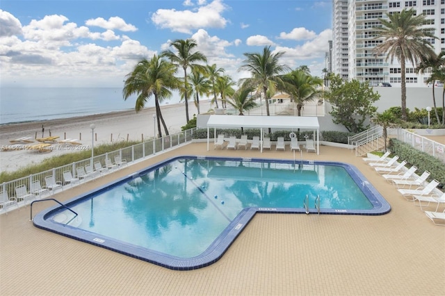 view of pool with a view of the beach, a water view, and a patio area