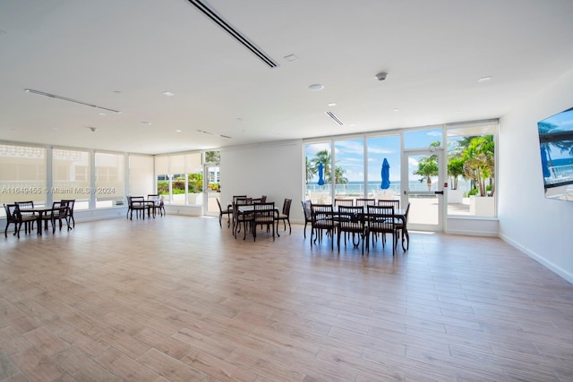 dining space with a wall of windows and light hardwood / wood-style flooring