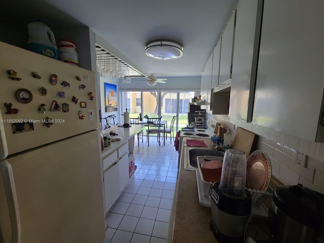 kitchen with white appliances, light tile patterned floors, decorative backsplash, white cabinetry, and ceiling fan