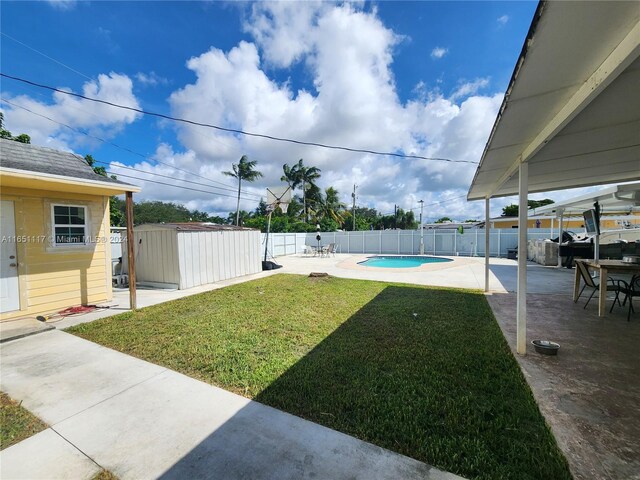 view of yard with a fenced in pool, a shed, and a patio