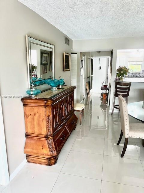 6100 NW 44th St Unit 405, Lauderhill, FL 33319 - corridor featuring a textured ceiling, baseboards, and light tile patterned floors