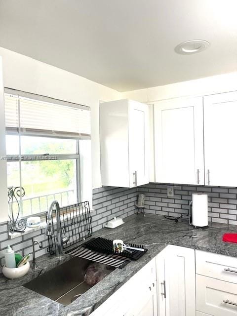 kitchen with dark stone counters, decorative backsplash, and white cabinetry