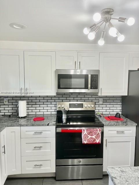 kitchen featuring decorative backsplash, light stone countertops, stainless steel appliances, and white cabinets