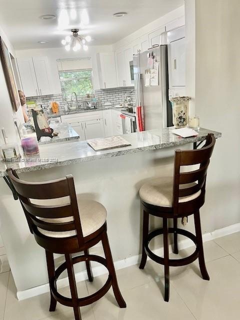 kitchen with kitchen peninsula, white cabinetry, stainless steel appliances, and a breakfast bar