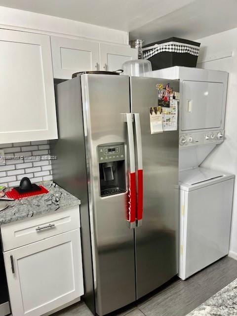 kitchen with decorative backsplash, white cabinets, stacked washer and dryer, light hardwood / wood-style flooring, and stainless steel fridge with ice dispenser