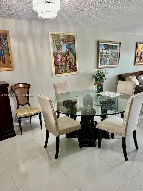 dining area with an inviting chandelier, a textured ceiling, and light tile patterned floors