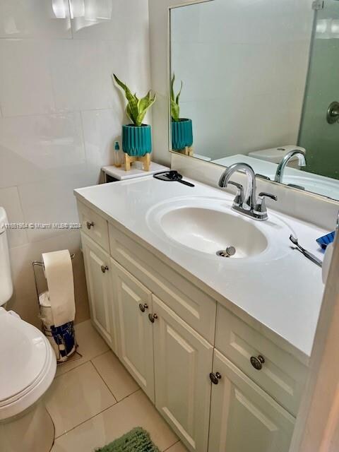 bathroom with tile walls, vanity, toilet, and tile patterned floors