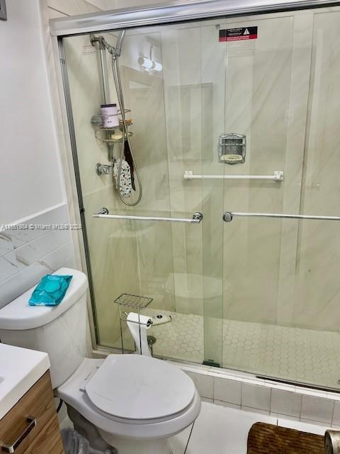 6100 NW 44th St Unit 405, Lauderhill, FL 33319 - bathroom with vanity, toilet, a shower stall, and tile walls