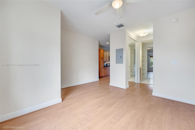 spare room featuring electric panel, ceiling fan, and light wood-type flooring