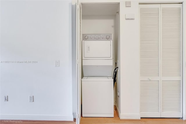 washroom with stacked washer / dryer and light hardwood / wood-style floors