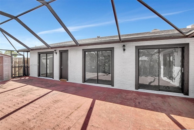 rear view of property featuring glass enclosure and a patio