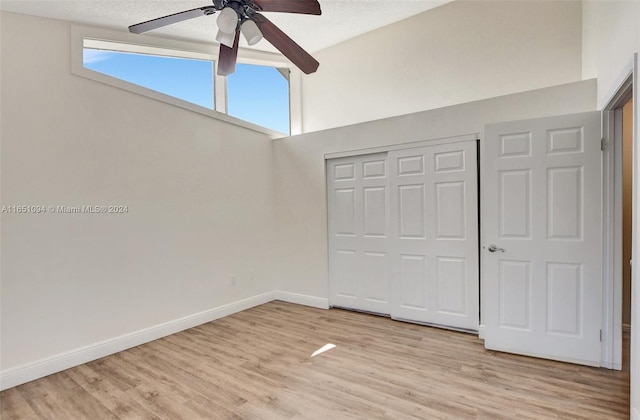 unfurnished bedroom with light wood-type flooring, a textured ceiling, ceiling fan, and a closet