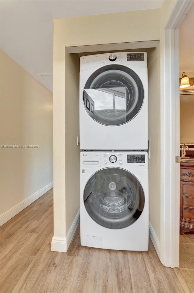 clothes washing area featuring stacked washer and dryer and light hardwood / wood-style floors