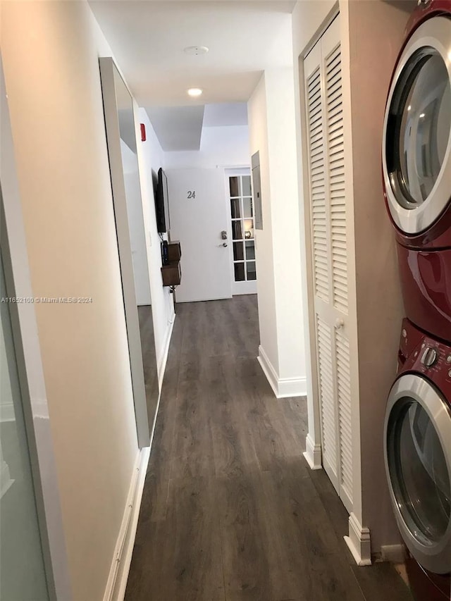 clothes washing area with dark wood-type flooring and stacked washer / drying machine