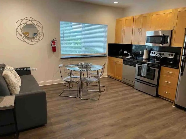 kitchen with backsplash, sink, dark wood-type flooring, appliances with stainless steel finishes, and light brown cabinets