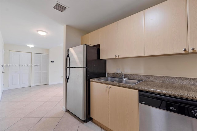 kitchen with light tile patterned floors, light brown cabinets, stainless steel appliances, and sink