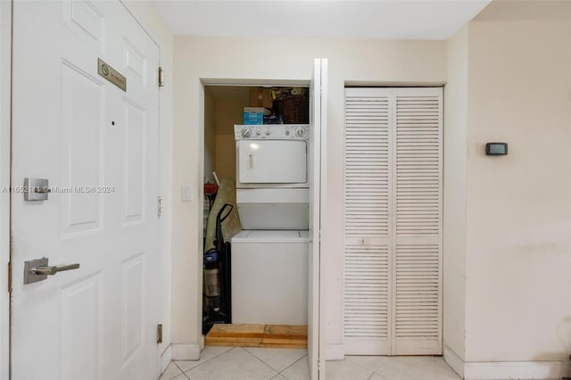 laundry room featuring stacked washer and clothes dryer and light tile patterned flooring