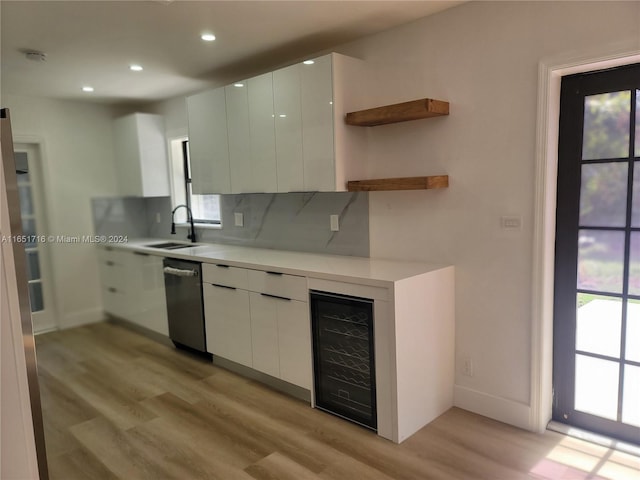 kitchen with light hardwood / wood-style flooring, beverage cooler, decorative backsplash, and white cabinets