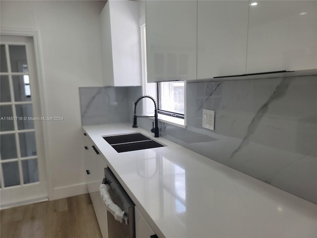 kitchen featuring light wood-type flooring, sink, white cabinets, and decorative backsplash