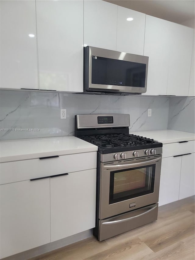 kitchen featuring white cabinetry, stainless steel appliances, decorative backsplash, and light hardwood / wood-style floors