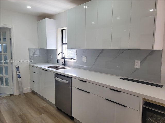 kitchen with light wood-type flooring, stainless steel dishwasher, white cabinetry, and sink