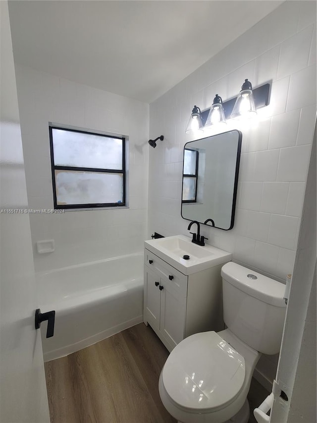 full bathroom with hardwood / wood-style floors, bathtub / shower combination, toilet, tile walls, and vanity