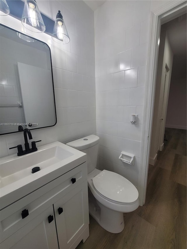 bathroom with tile walls, toilet, vanity, and hardwood / wood-style flooring