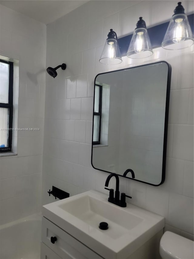 full bathroom with vanity, toilet, tile walls, and tiled shower / bath