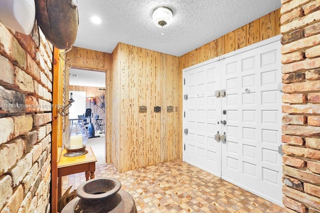 foyer featuring a textured ceiling and wood walls