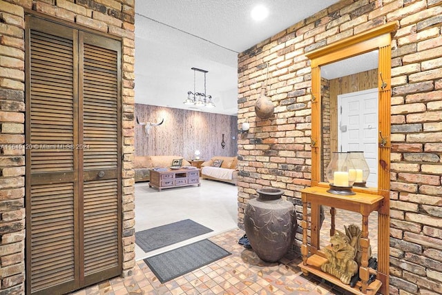 interior space featuring brick wall, wood walls, an inviting chandelier, and a textured ceiling