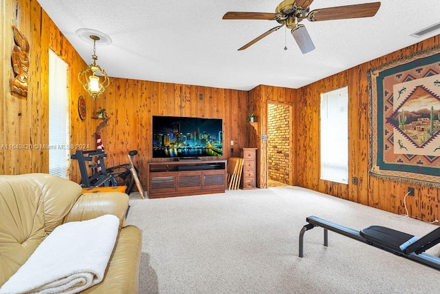 living room featuring carpet flooring, ceiling fan, and wood walls