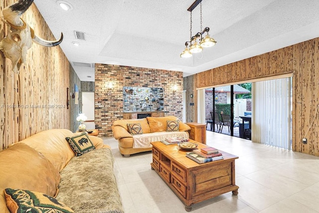 living room with a raised ceiling, a textured ceiling, a chandelier, and wood walls