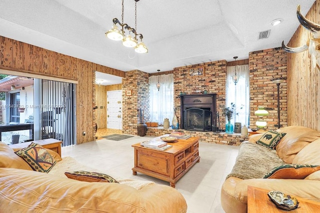 tiled living room with a textured ceiling, a brick fireplace, and wood walls