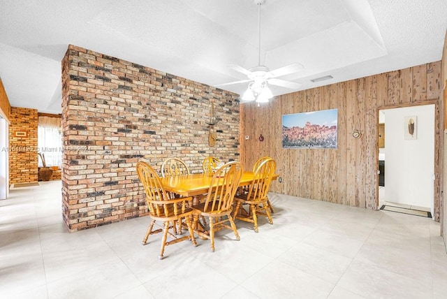 unfurnished dining area with ceiling fan, wooden walls, and brick wall