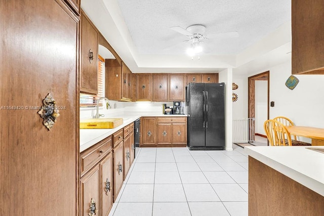 kitchen featuring a textured ceiling, black appliances, light tile patterned floors, sink, and ceiling fan