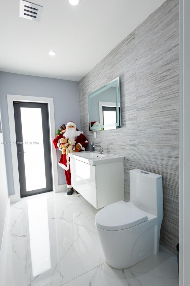 bathroom with tile walls, vanity, and toilet