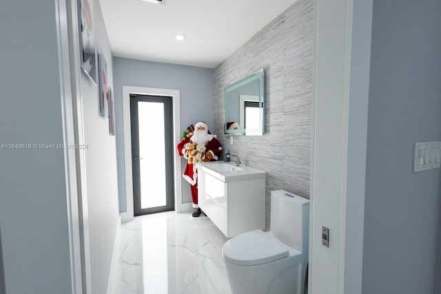 bathroom with tile walls, vanity, and toilet