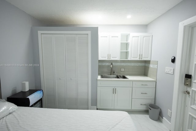 bedroom with a textured ceiling, a closet, and sink