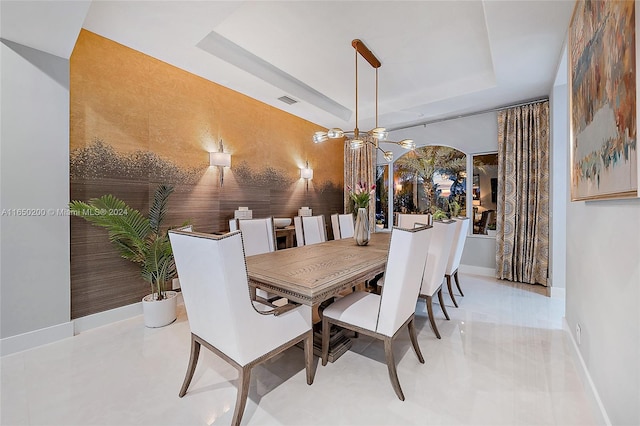 dining space with a notable chandelier and a tray ceiling