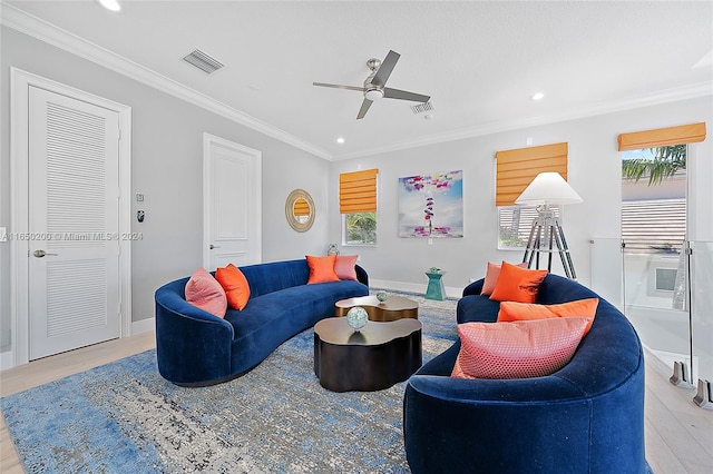 living room featuring ceiling fan, ornamental molding, and light wood-type flooring