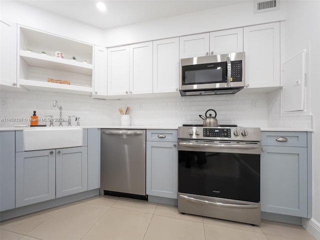 kitchen with appliances with stainless steel finishes, sink, light tile patterned floors, and gray cabinetry