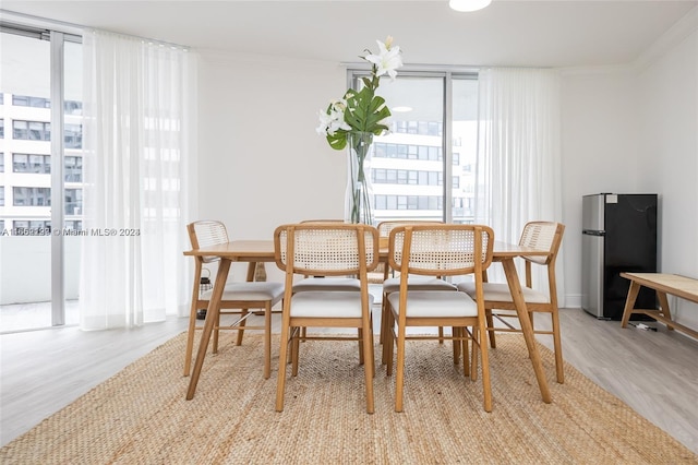 dining space with crown molding, light wood-type flooring, and floor to ceiling windows