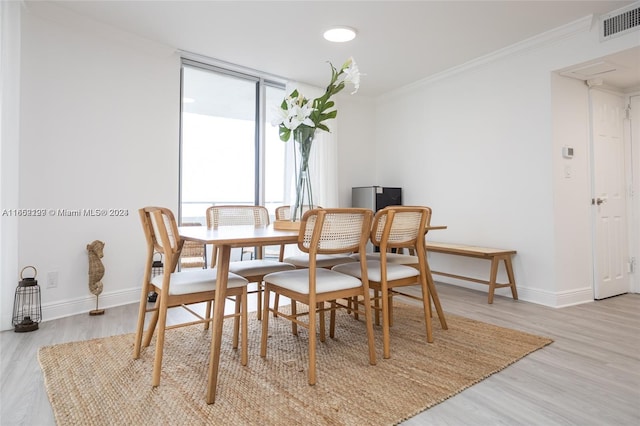 dining space with light wood finished floors, crown molding, baseboards, and visible vents