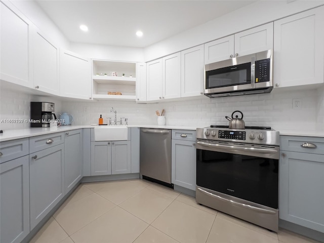 kitchen featuring light tile patterned floors, appliances with stainless steel finishes, sink, gray cabinets, and decorative backsplash