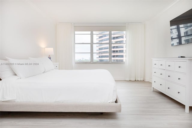 bedroom featuring light wood-type flooring, baseboards, and ornamental molding