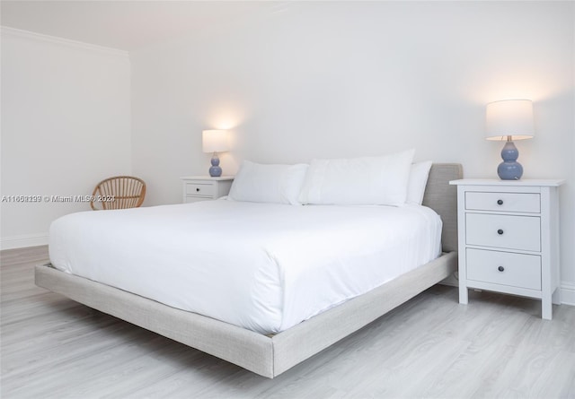 bedroom featuring baseboards, light wood finished floors, and crown molding
