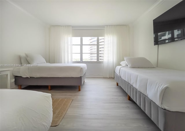 bedroom with ornamental molding and light wood-type flooring