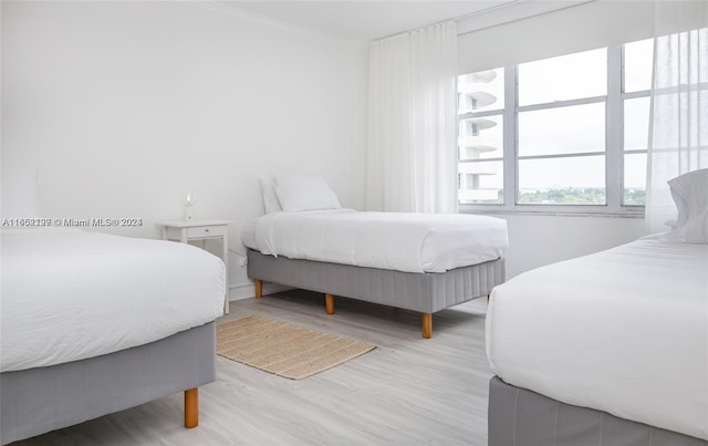 bedroom featuring ornamental molding and light hardwood / wood-style flooring