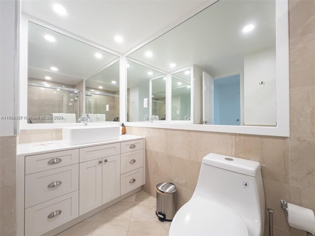 bathroom with vanity, toilet, tile walls, and a shower with shower door